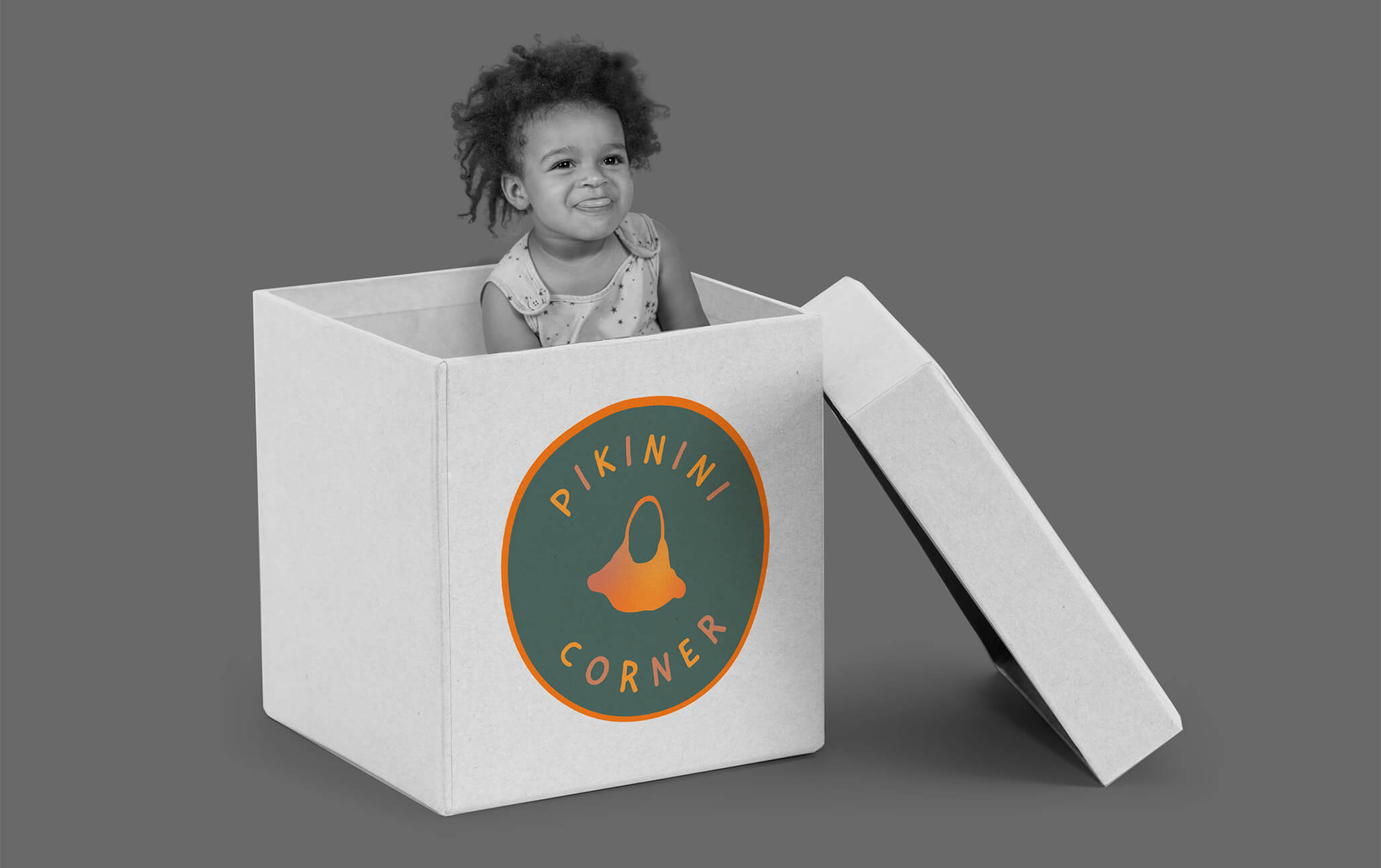 Little girl with curly hair popping out of large box